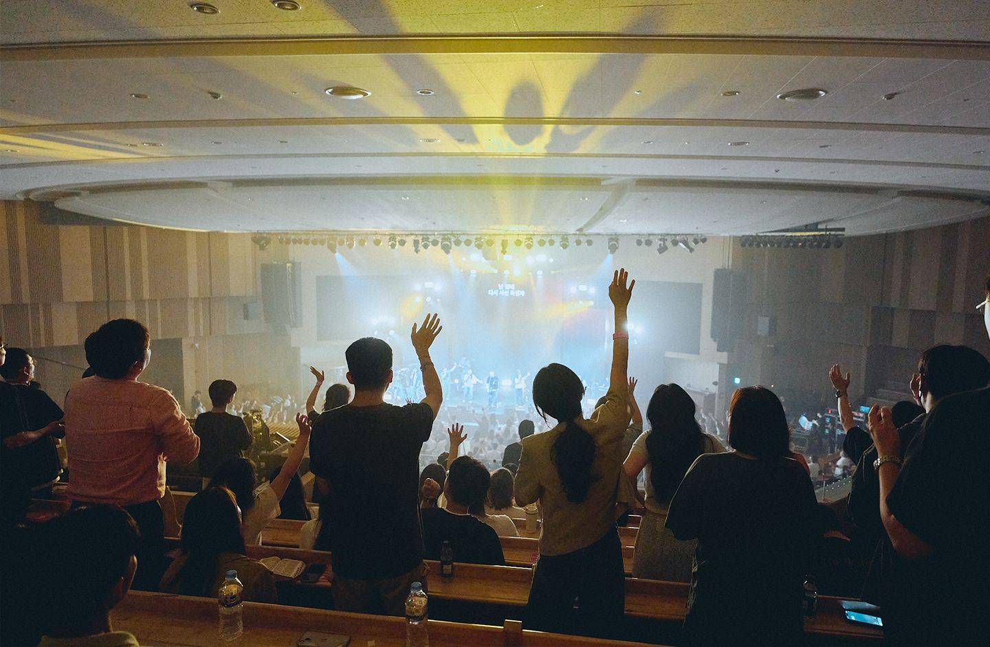 Picture of worshippers with hands raised in a large Korean church service